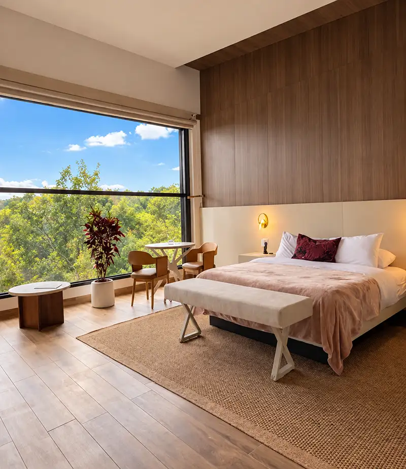 Dormitorio de Canopy Suite con ventanales de piso a techo hacia las copas de los árboles