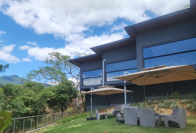 Exterior de Canopy Suite con patio de césped, sombrillas y montañas al fondo