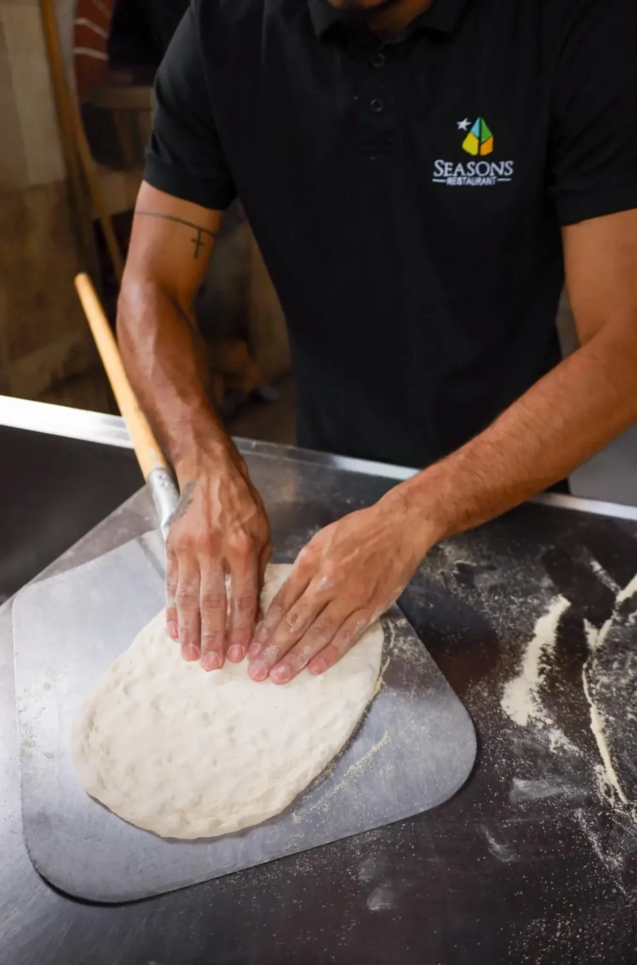 Seasons chef hand-shaping pizza dough in the wood-fired kitchen